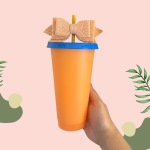 Orange plastic cup with a blue lid, straw and bow