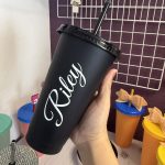 Finished black plastic cup with a personalized name held in a hand