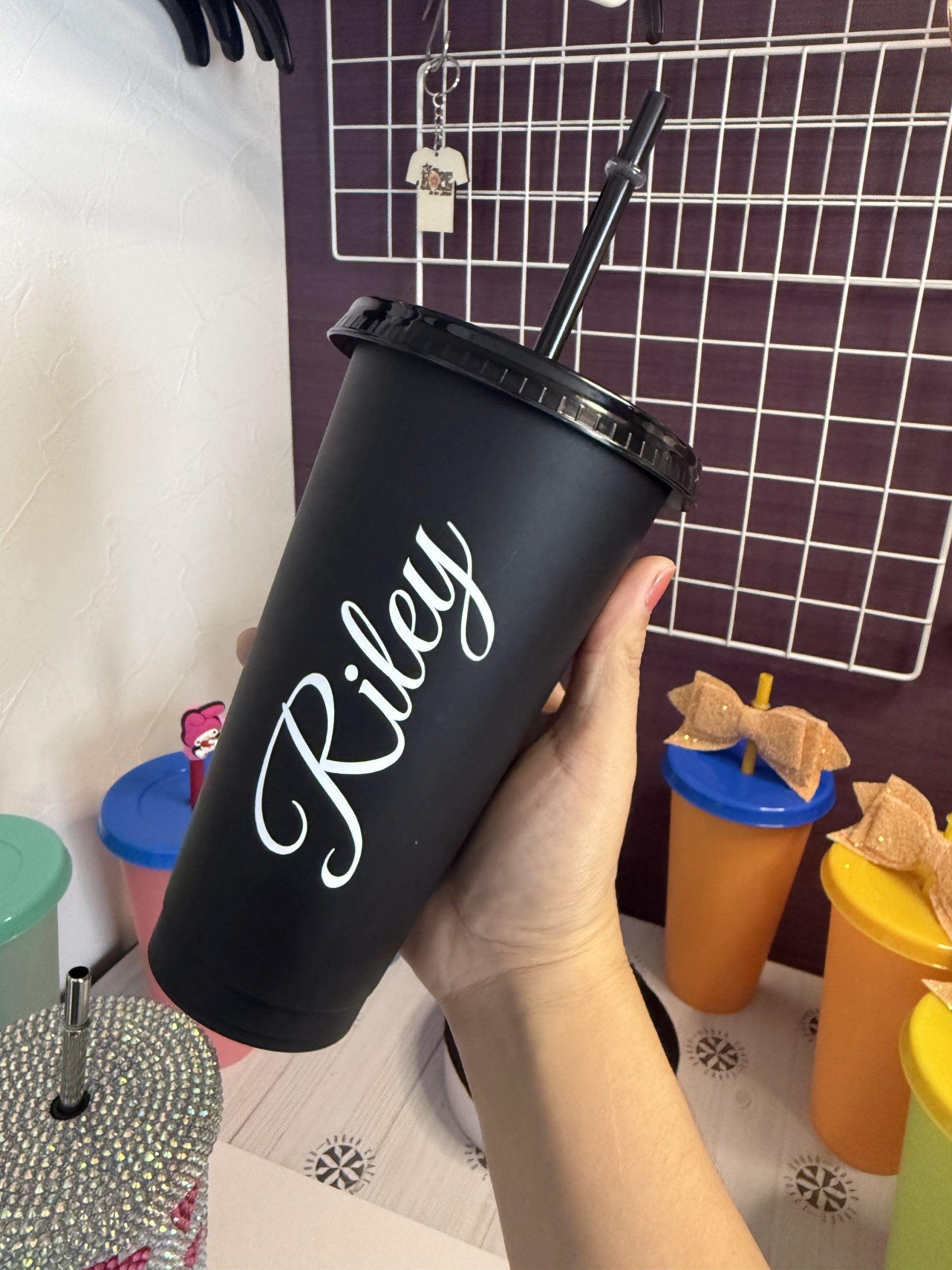 Finished black plastic cup with a personalized name held in a hand