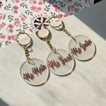 Round acrylic name keychains displayed with gold-colored rings